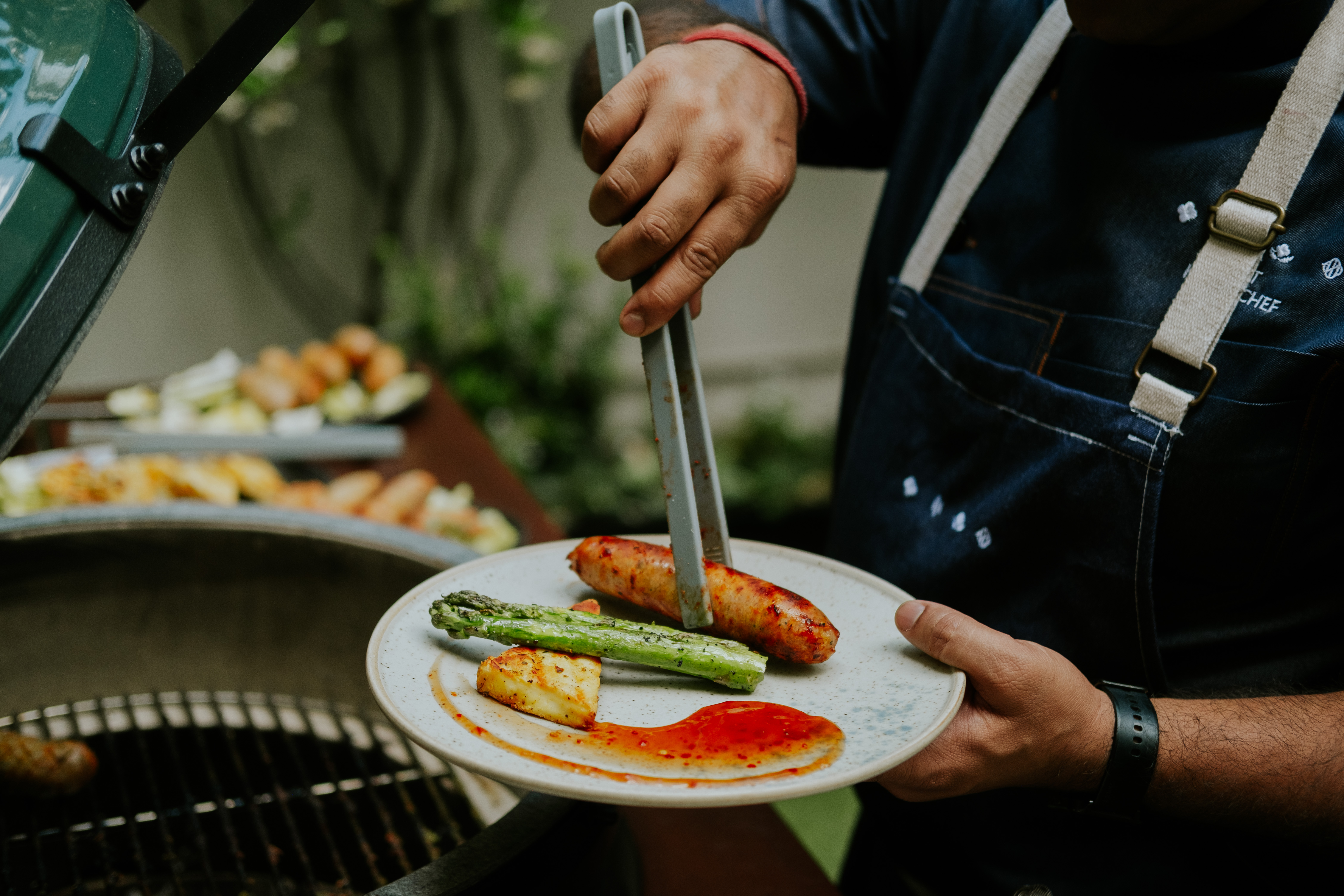 Chef plating grilled food at The Hyde Garden, Roseate House London for outdoor events.