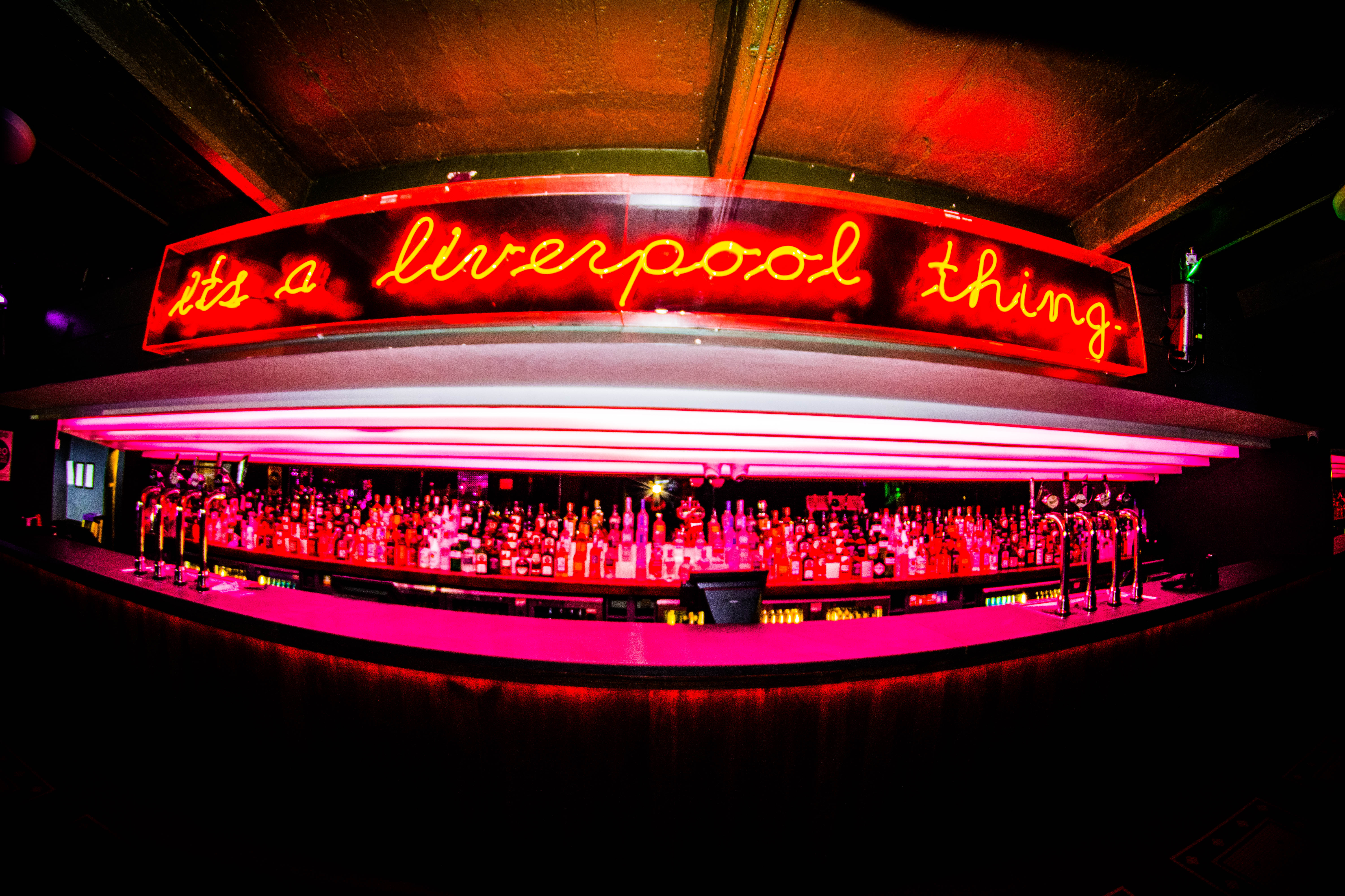 Vibrant bar venue with neon sign, ideal for networking events and social gatherings. - Banner