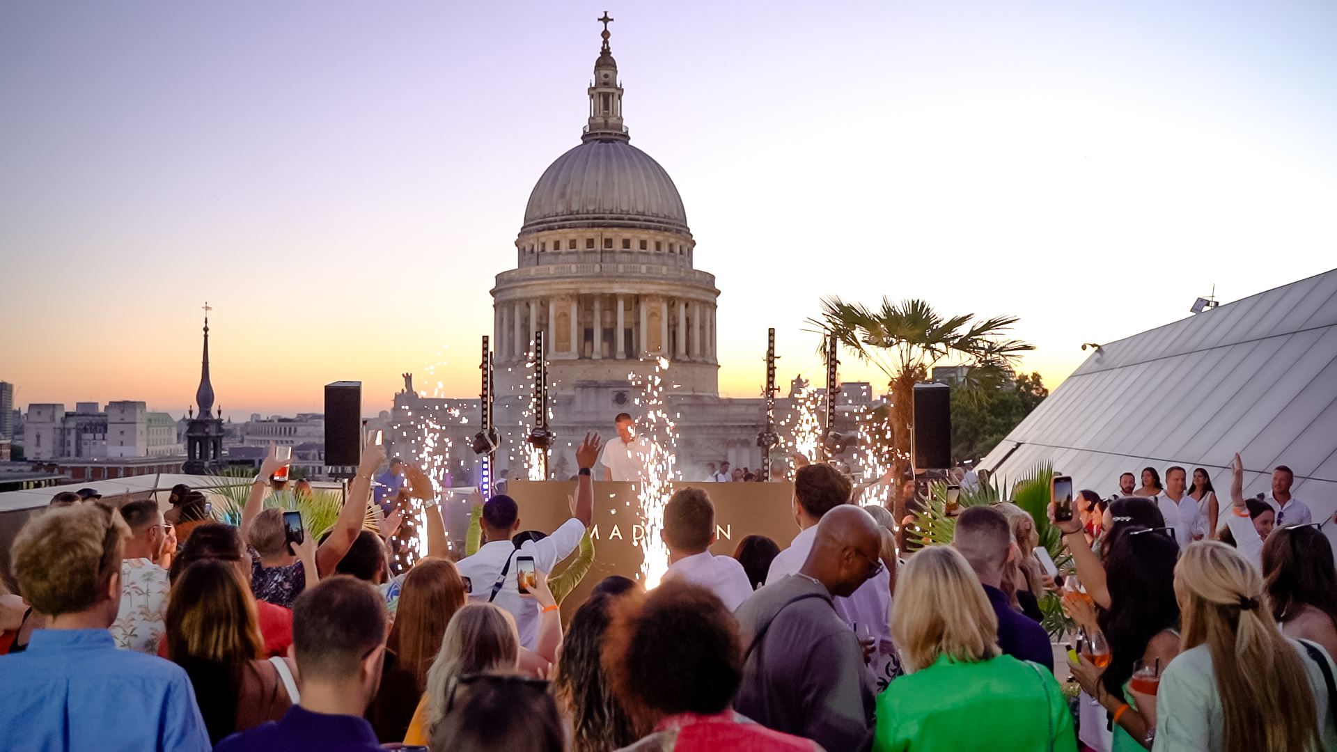 Vibrant rooftop event at Whole Venue, Madison with sparklers and St. Paul's Cathedral backdrop.