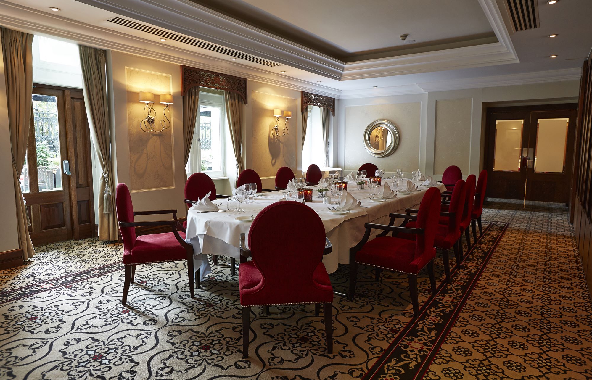 Elegant meeting room with round tables and red chairs, ideal for corporate events.