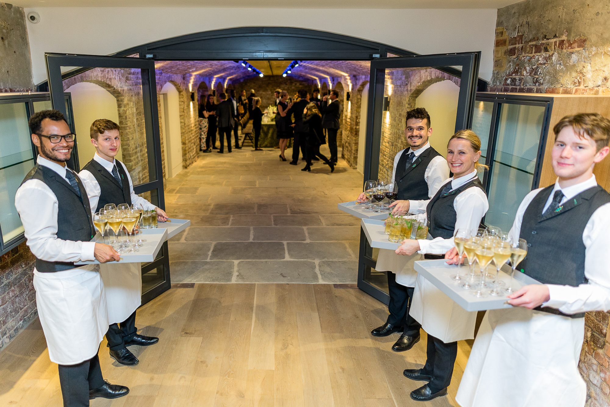 Servers with drink trays at a London Bridge Arches corporate event in Glaziers Hall. - Banner