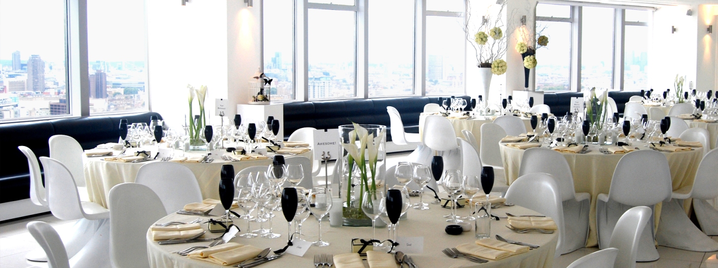 Elegant event space at Altitude 360, featuring round tables and white floral centerpieces.