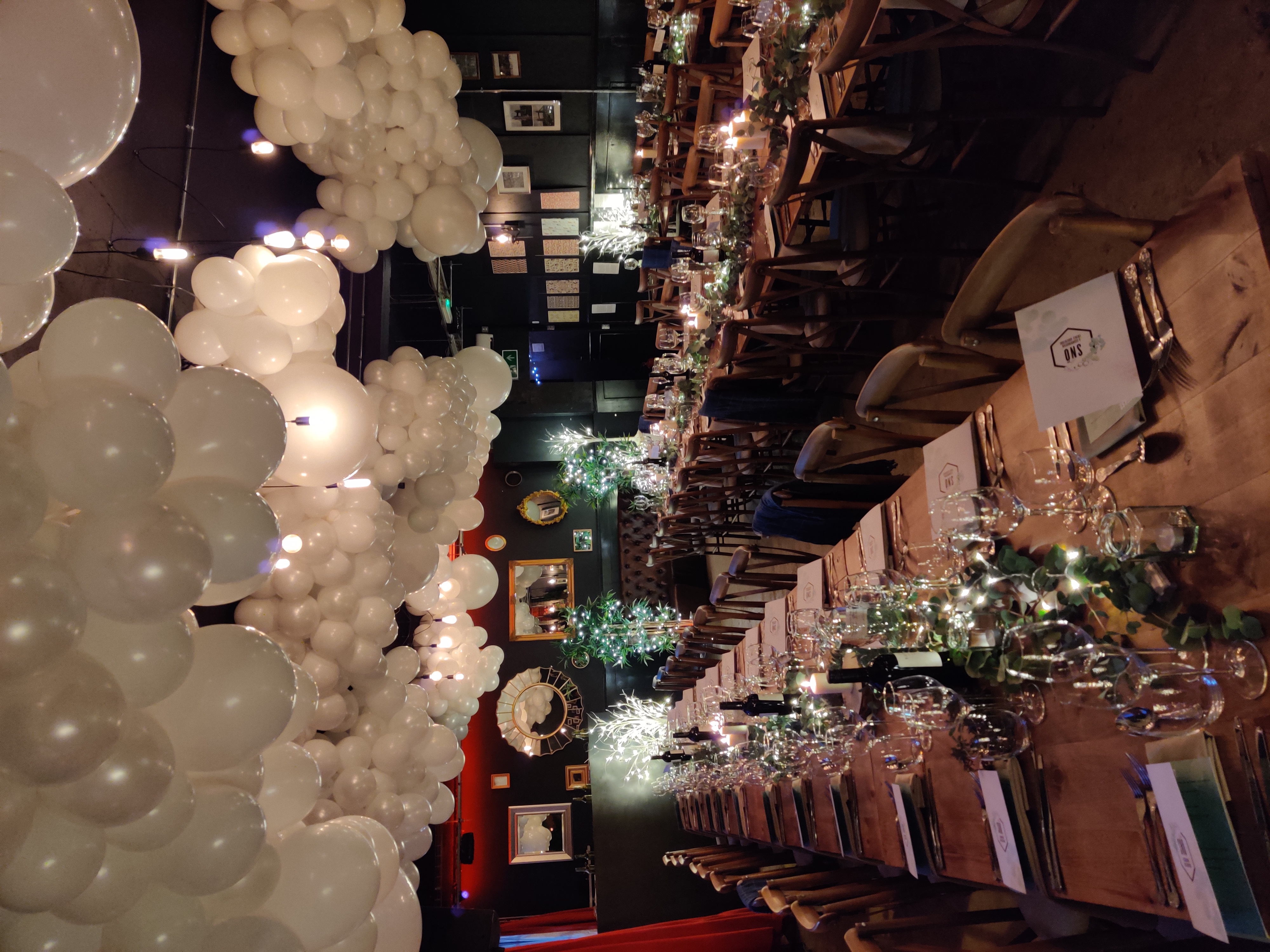 Elegant dining setup with candles and balloons for weddings and corporate events.