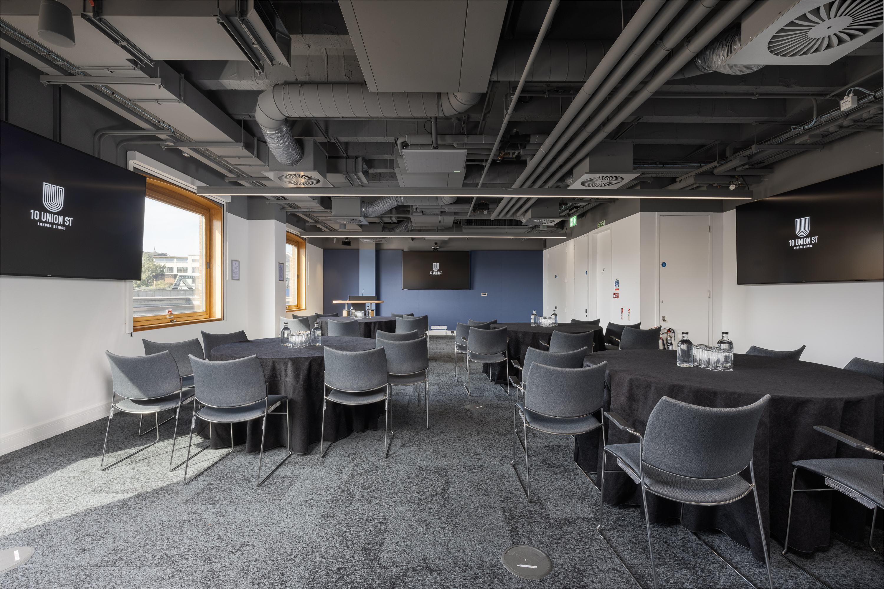 Industrial-chic meeting room with round tables for collaborative workshops and corporate events.