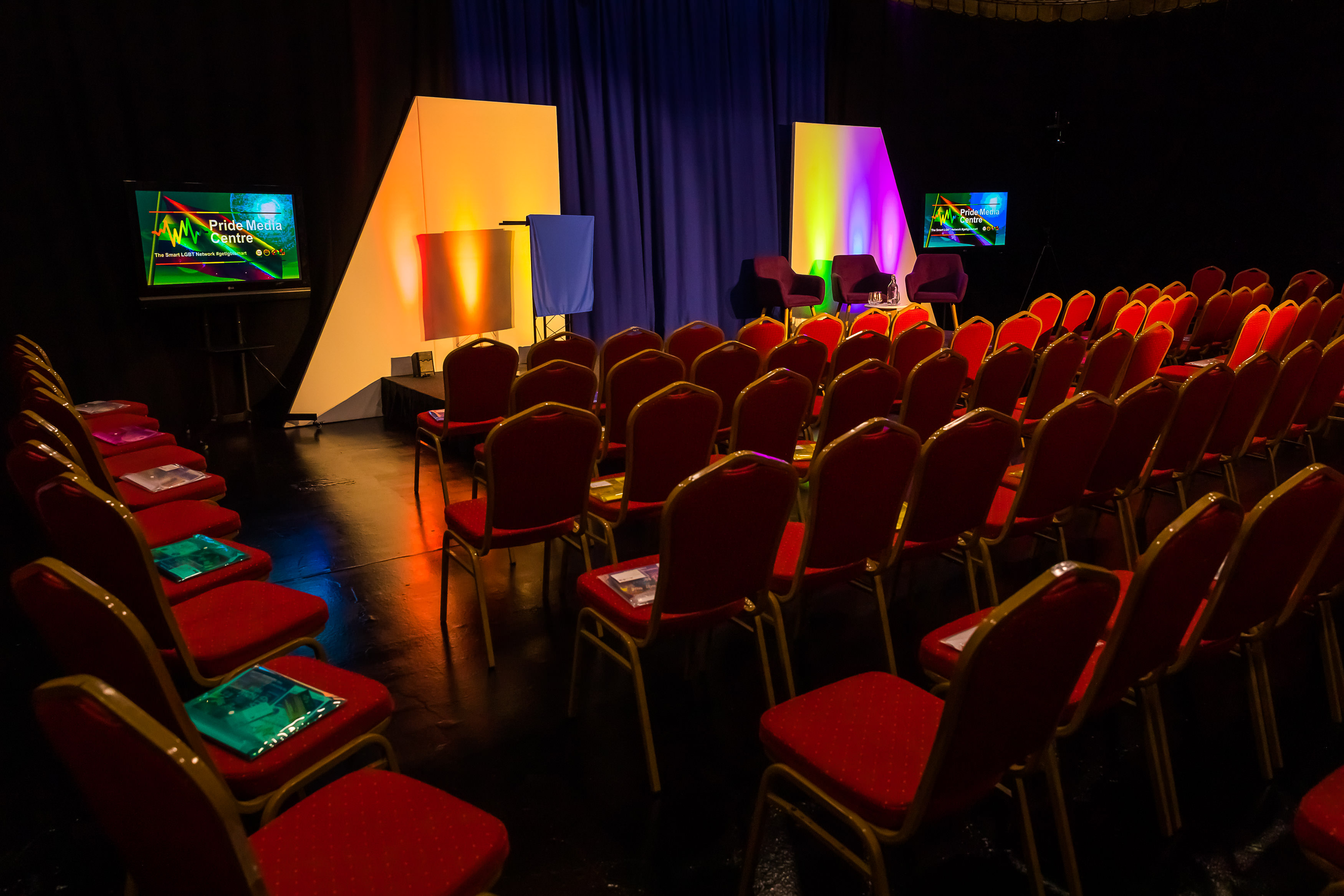 TV studio event space with vibrant backdrop and red chairs for engaging conferences. - Banner
