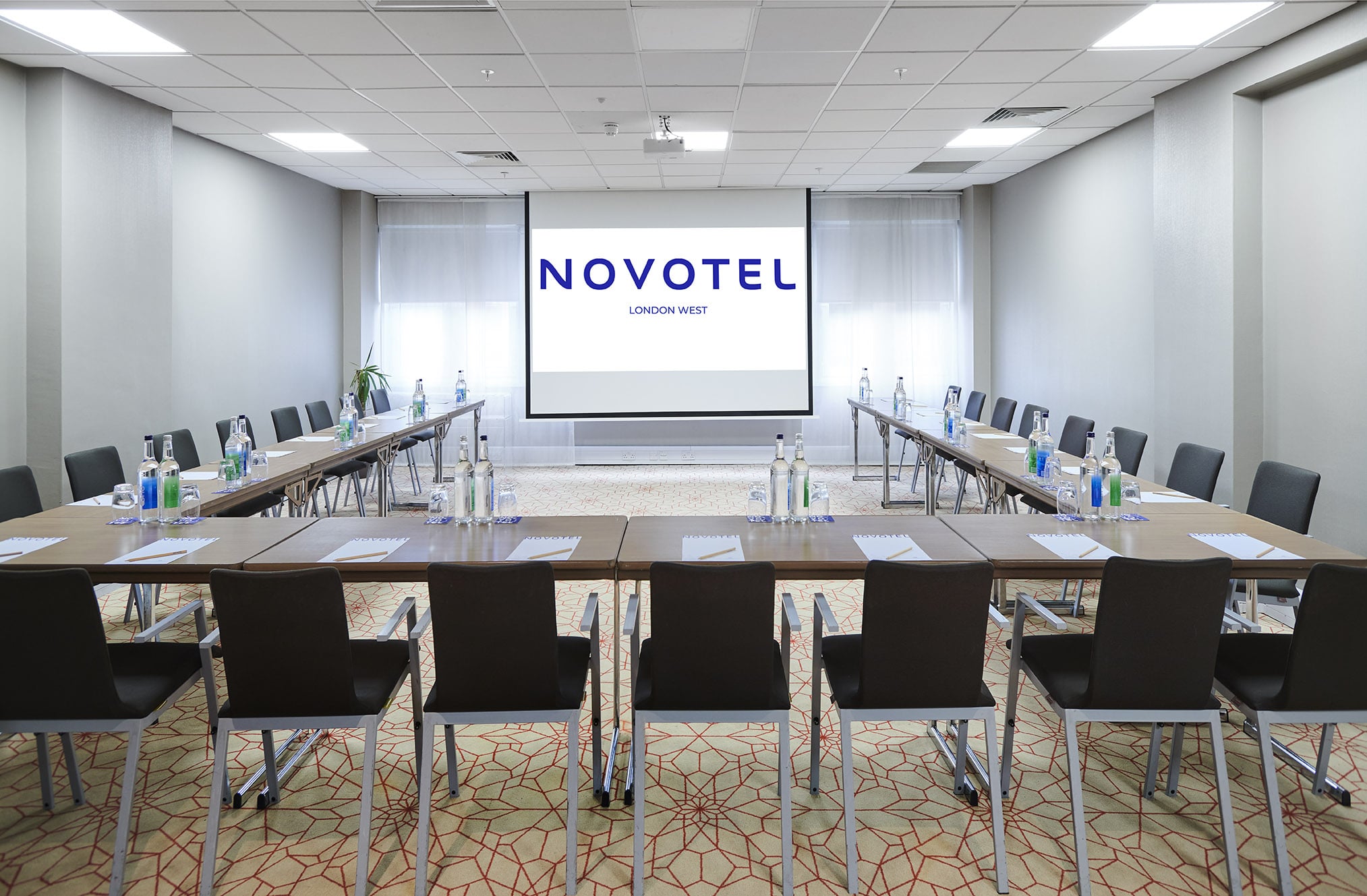 Well-arranged Novotel meeting room with presentation screen for professional events.