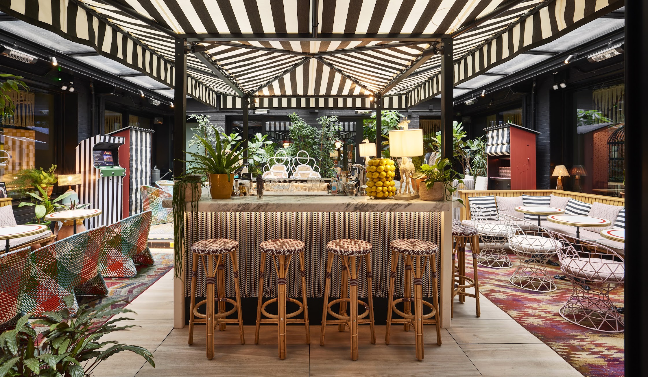 Stylish Garden Bar at Mama Shelter London with striped canopy, perfect for events and gatherings.