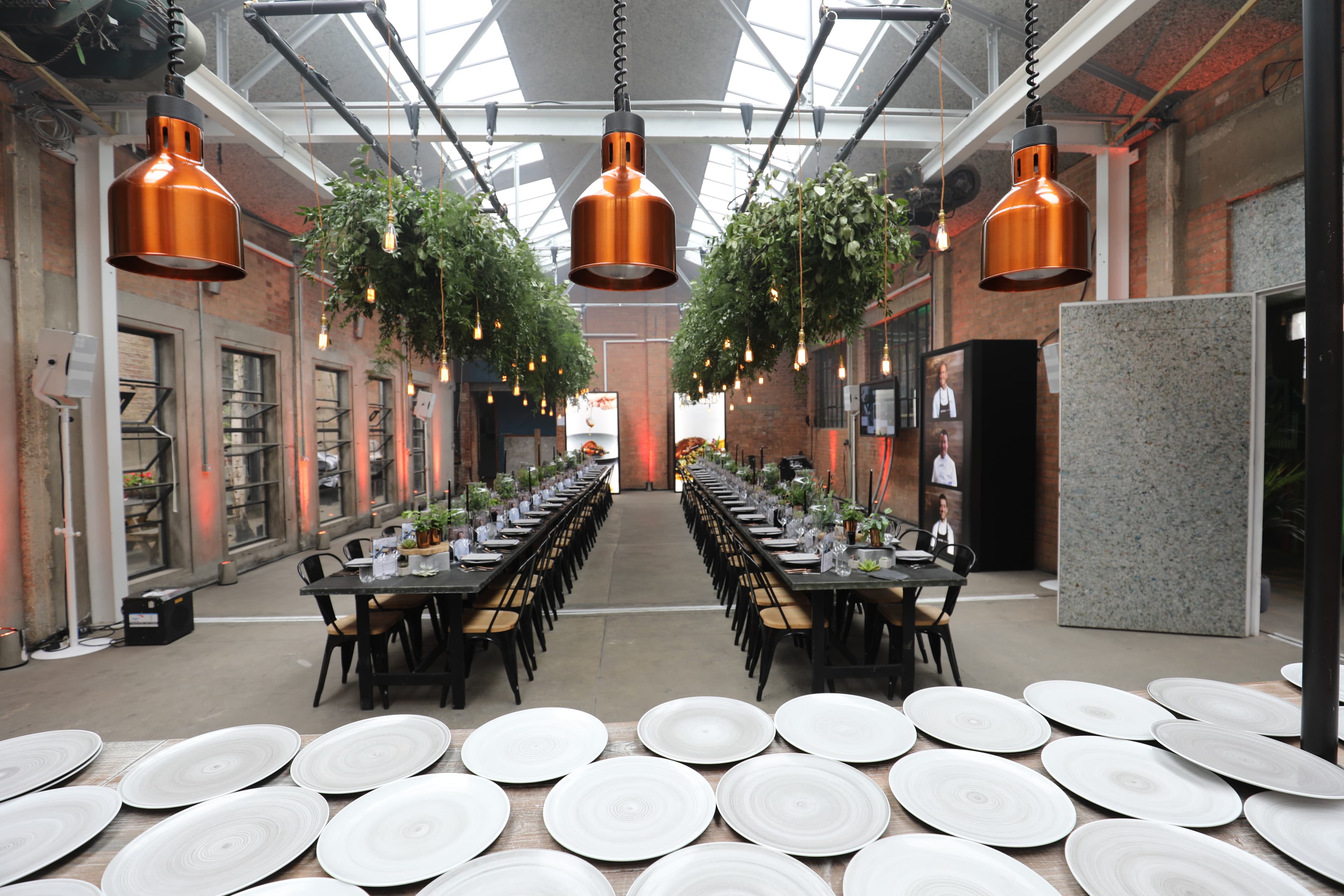 Industrial event space at Hoxton Docks with long-table gala dinner seating and pendant lighting.