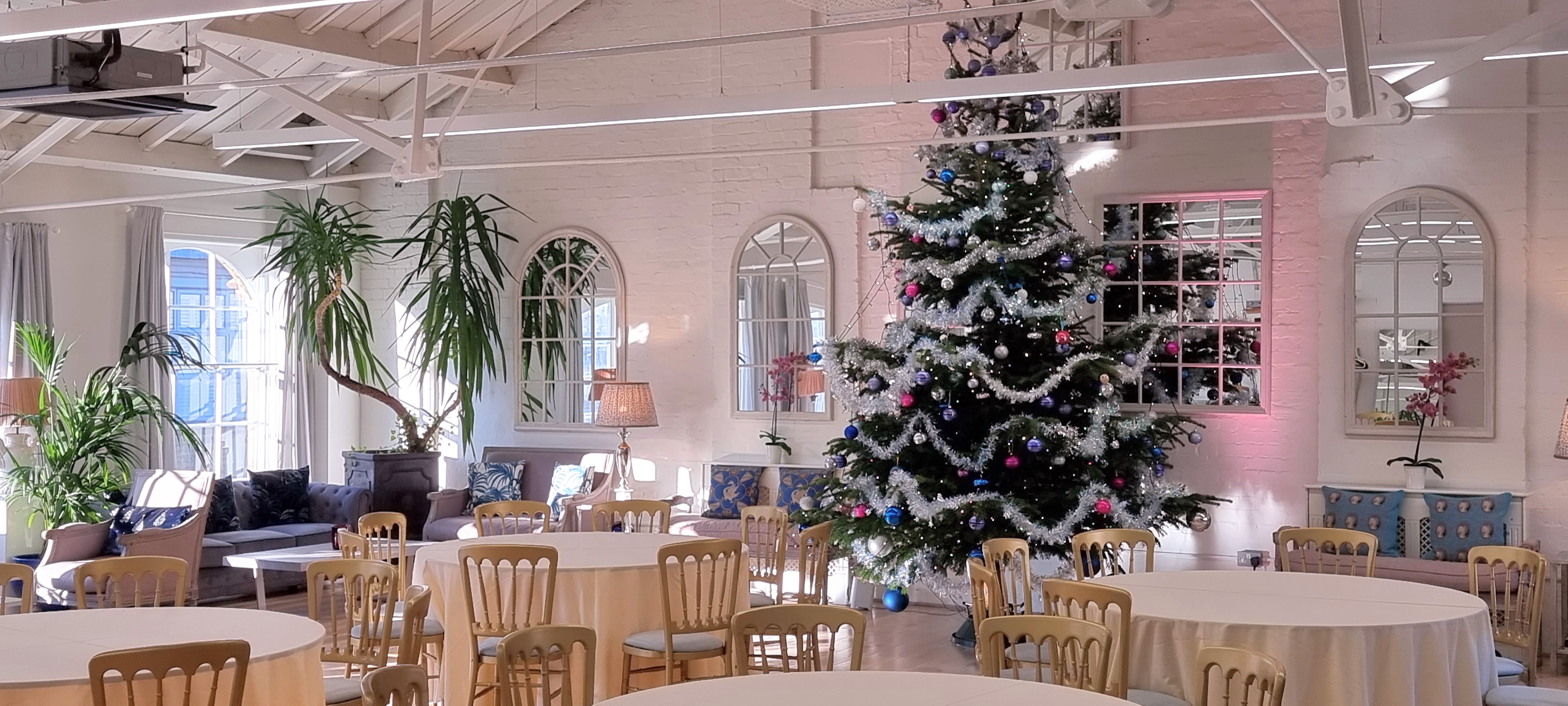 Lumiere Underwood Christmas event space with festive tree, high ceilings, and arched mirrors.