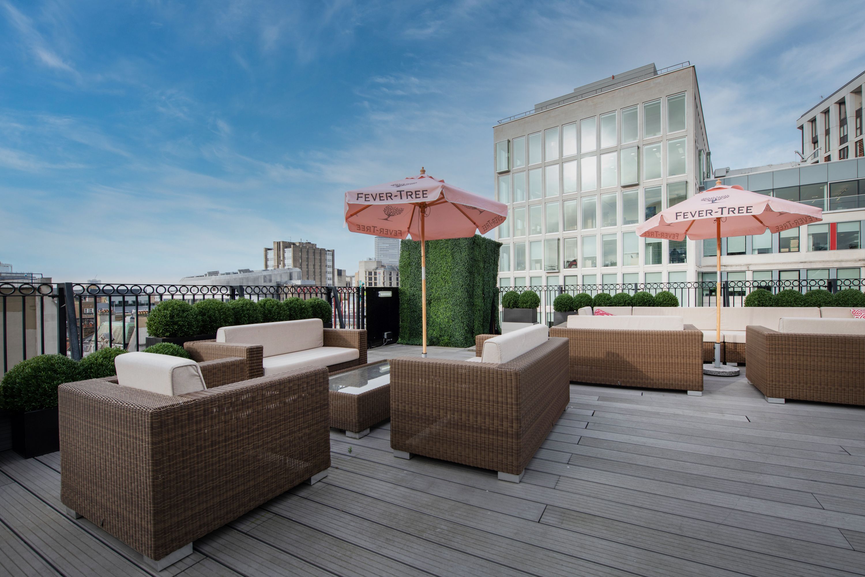Stylish rooftop event space with lounge seating and pink umbrellas at De Vere Grand Connaught Rooms.